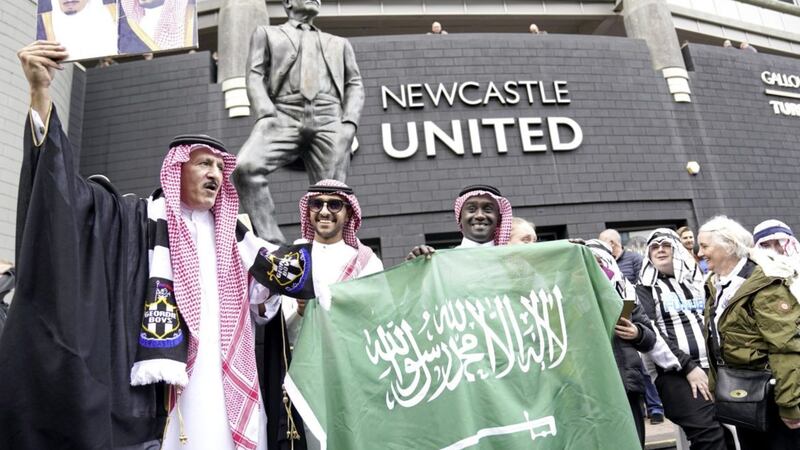Newcastle United fans outside the stadium hold up a Saudi Arabia flag ahead of the Premier League match at St. James&#39; Park, Newcastle. Picture date: Sunday October 17, 2021. 