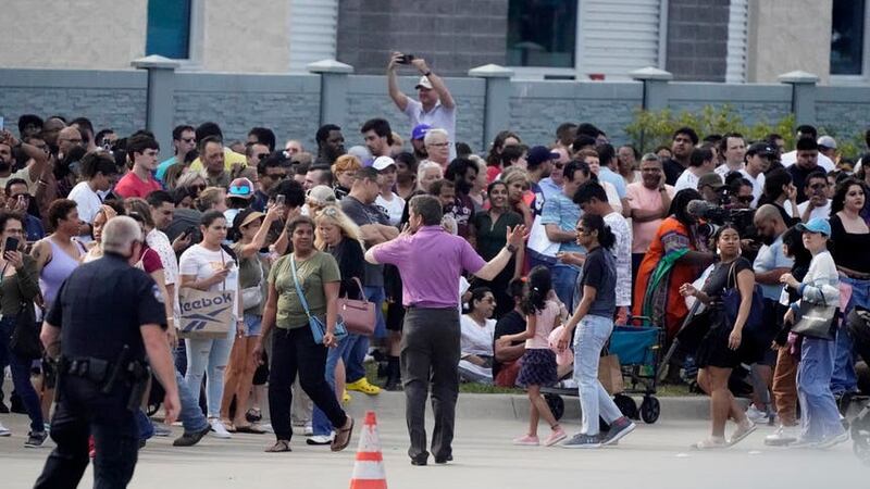 People gather across the street from the shopping centre after a shooting on May 6 (LM Otero/AP)