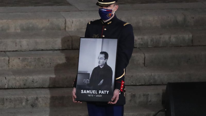 A Republican Guard holds a portrait of Samuel Paty in the courtyard of the Sorbonne university during a national memorial event (Francois Mori, Pool/AP)