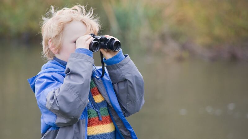 CRX7E4 Boy using binoculars in the countryside by a river