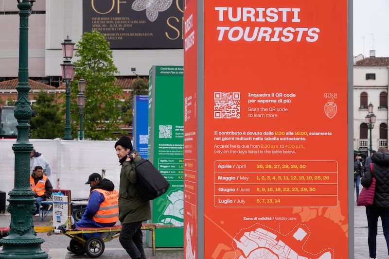 Tourist information boards are seen outside the main train station in Venice (Luca Bruno/AP)