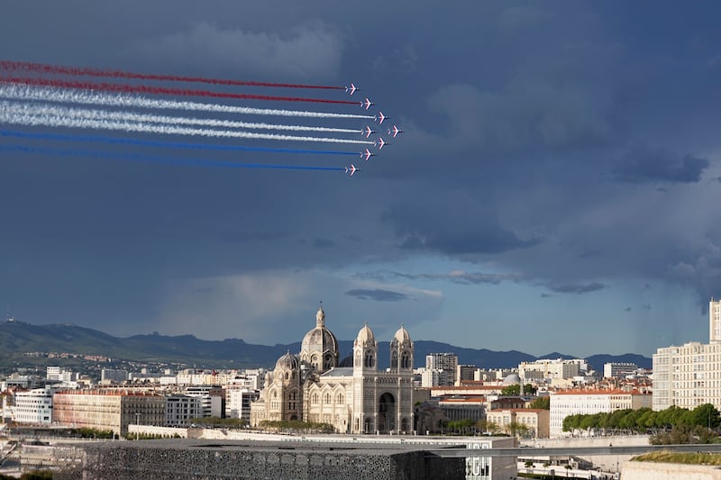 The Patrouille de France aerobatics demonstration aircraft leave a tricolor trail of smoke in the sky above La Major Cathedral as the Belem enters the Old Port in Marseille, southern France (Laurent Cipriani/AP)