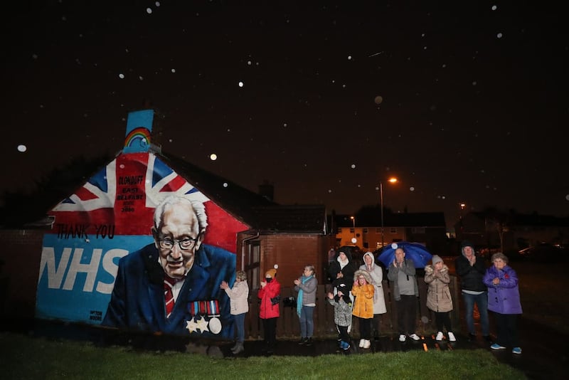 Local residents stand beside a mural of Captain Sir Tom Moore in Clonduff, east Belfast 