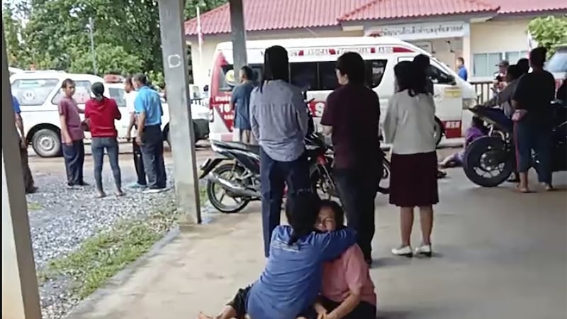 In this image taken from video, a distraught woman is comforted outside the site of an attack at a daycare center, Thursday, Oct. 6, 2022, in the town of Nongbua Lamphu, north eastern Thailand (Mungkorn Sriboonreung Rescue Group via AP)