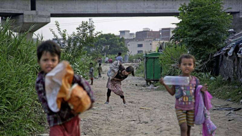 A Rohingya refugee girl tries to lift a sack containing food items, donated by locals, as she walks back to her shanty at a camp for the refugees in New Delhi, India PICTURE: Altaf Qadri/AP 