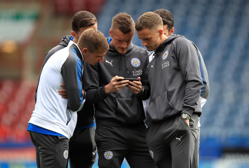Jamie Vardy and his Leicester team mates look at a phone