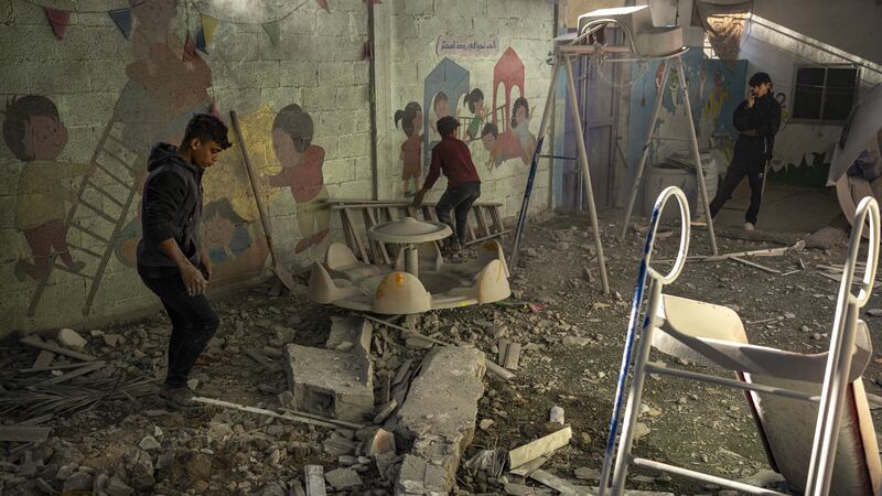 Palestinians look at buildings destroyed in the Israeli bombardment (Fatima Shbair/AP)