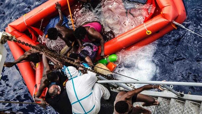 Rescuers help migrants to board the Italian Navy ship Vega, after the boat they were aboard sunk. The Italian navy says it has saved 135 migrants from a sinking boat and recovered 45 bodies in the Mediterranean. Picture by Raffaele Martino, Marina Militare/Associated Press