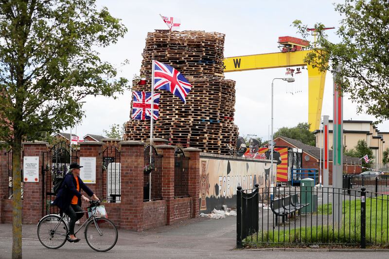&nbsp;A woman cycles past a bonfire on the Newtownards Road in Belfast as preparations are underway for the July 11th loyalist bonfires despite disagreement over whether they should take place during the coronavirus pandemic.