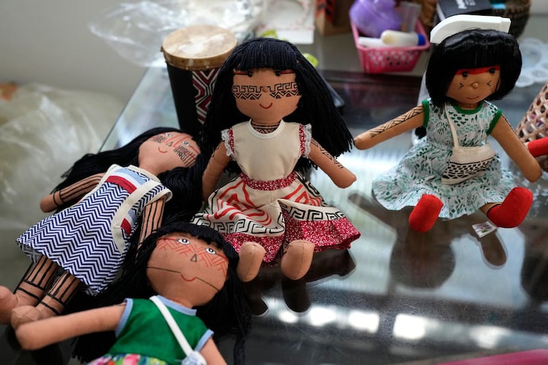 Dolls bearing faces and body paints of different indigenous groups are displayed on a table at a sewing workshop in Rio de Janeiro, Brazil 