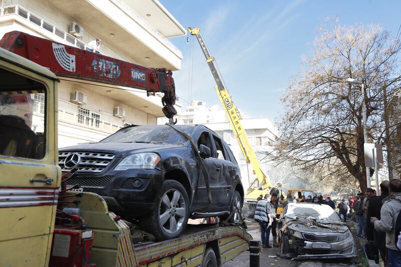 A destroyed vehicle is taken away from a building hit by an air strike in Damascus (Omar Sanadiki/AP)