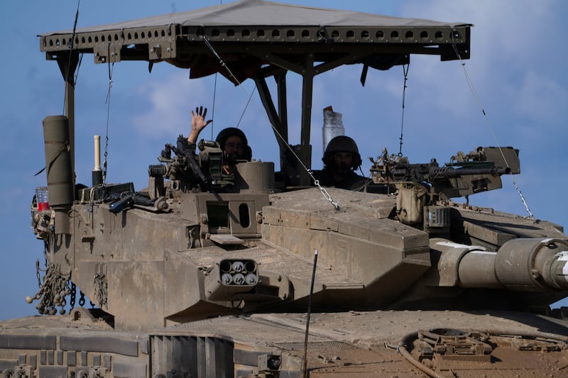 An Israeli soldier waves from his tank in southern Israel near the Gaza border (AP)