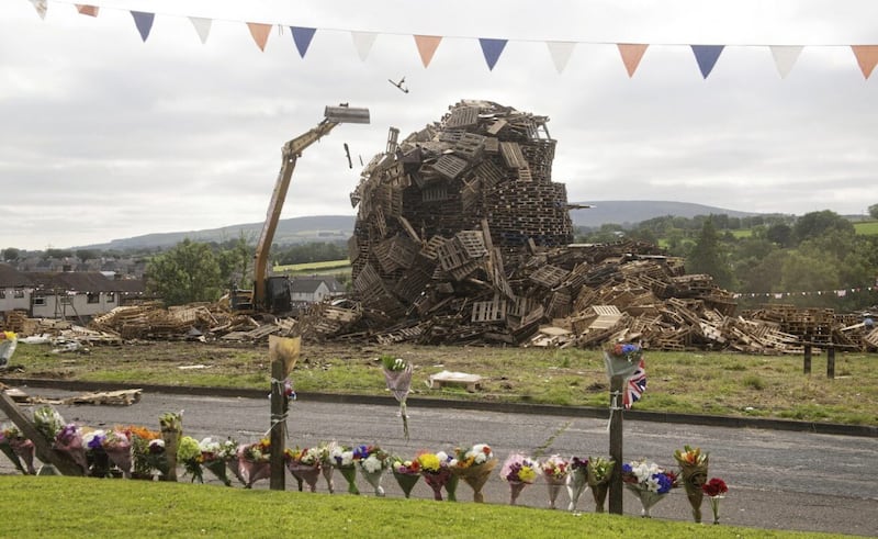 A telescopic digger knocks down the Antiville bonfire after the death of John Steele last year