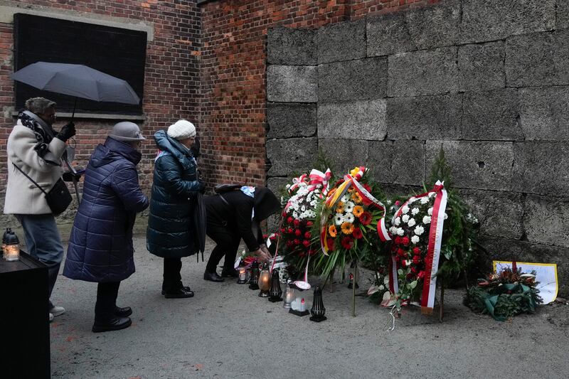 Holocaust survivors and relatives light candles at the Death Wall in the Auschwitz Nazi death camp in Oswiecim, Poland (AP Photo/Czarek Sokolowski)