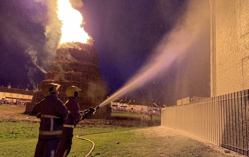 Firefighters dousing a block of flats in Portadown with foam as a bonfire rages close by.
