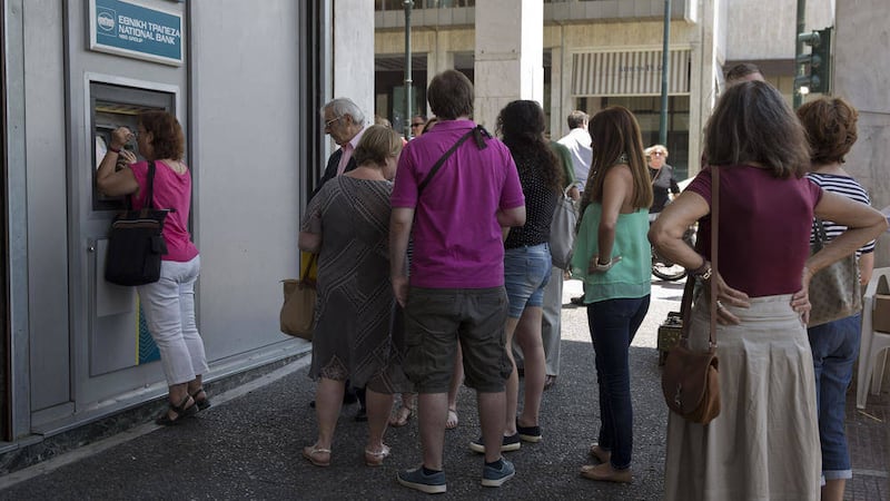 People line up at an ATM outside a National bank branch, in central Athens. Anxious Greeks lined up at ATMs as they gradually began dispensing cash again on the first day of capital controls imposed in a dramatic twist in Greece s five-year financial saga 
