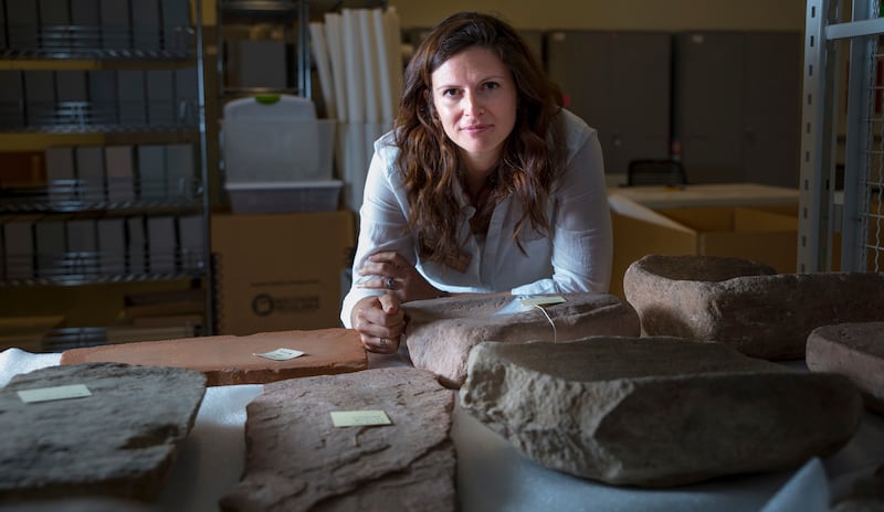 Lisbeth Louderback, assistant professor of anthropology and curator of archaeology at the Natural History Museum of Utah, stands behind large stone metates, the grindstones on which ancient Native Americans processed their food. 