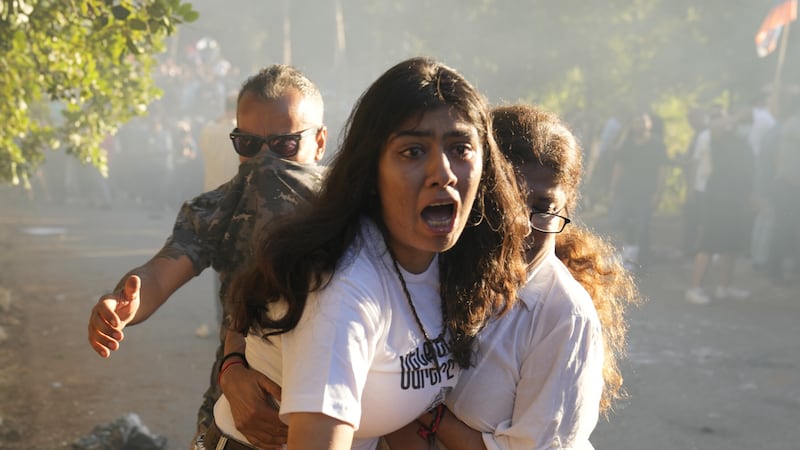 A Lebanese Armenian woman reacts to tear gas outside the Azerbaijani embassy in Beirut (Hussein Malla/AP)