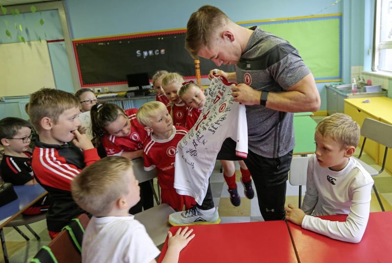 Teacher and Tyrone footballer Mark Bradley shows pupils from St Mary&#39;s PS, Pomeroy his signed All-Ireland semi-final jersey which was donated for a school raffle. Picture by Hugh Russell 