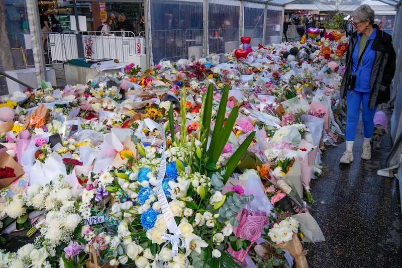 A woman walks past flowers at a tribute for the victims of Saturday’s knife attack (Mark Baker/AP)