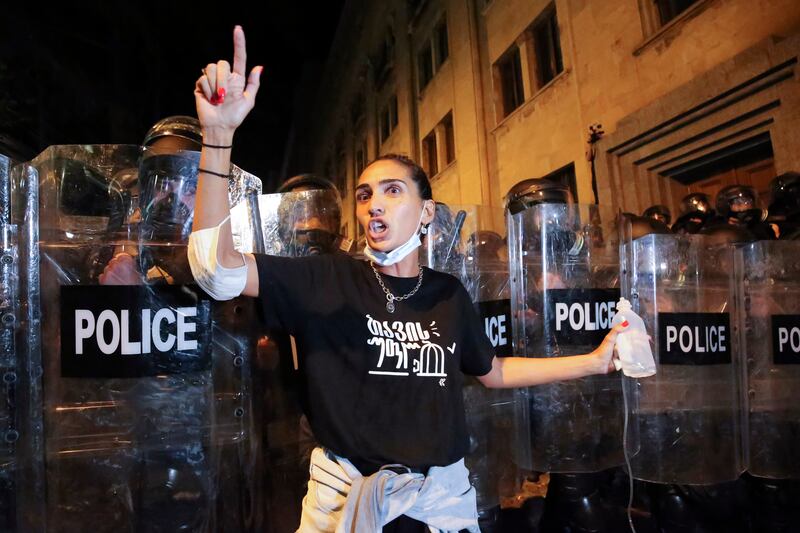 A demonstrator gestures while standing in front of the police line (Zurab Tsertsvadze/AP)