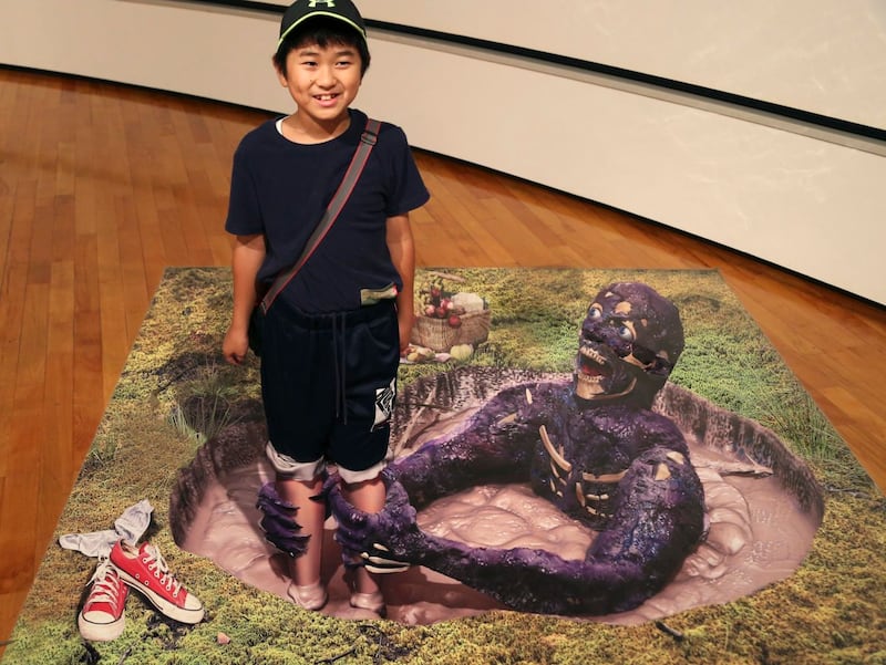 A boy poses with a 3D image at a 3D trick art exhibition by Japanese artist Masashi Hattori in Kawasaki, near Tokyo, Saturday, Aug. 5, 2017. (Koji Sasahara/AP/PA