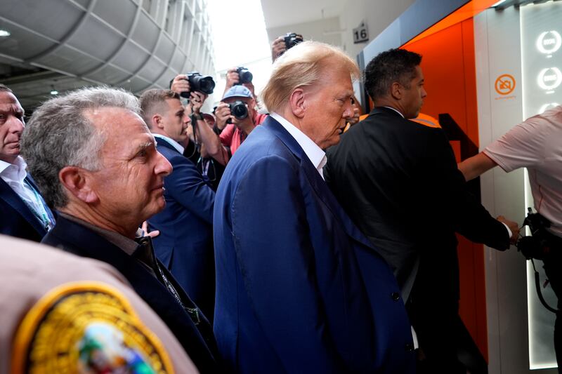 Donald Trump, centre, arrives at the McLaren garage (Rebecca Blackwell/AP)