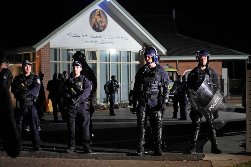 Security officers stand guard outside the Orthodox Assyrian church on Monday night (Mark Baker/AP)