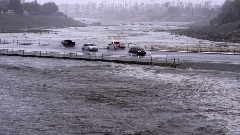 Vehicles cross over a flood control basin that has almost reached the street in Palm Desert, California (Mark J. Terrill, AP)