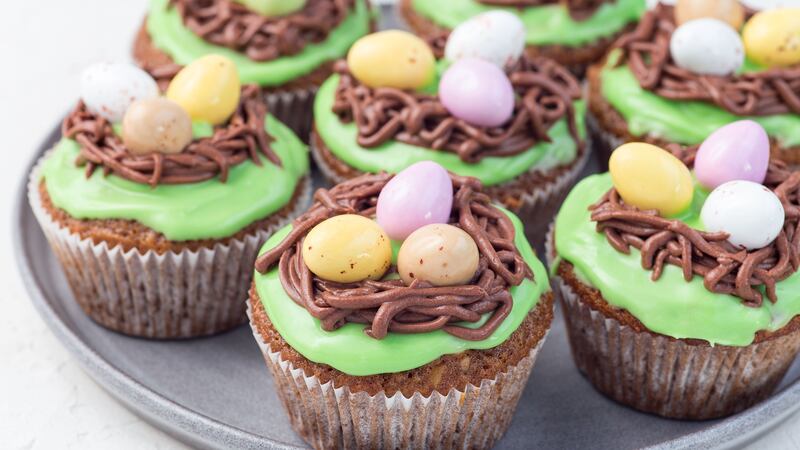 Carrot cupcakes with cream cheese frosting and Easter chocolate eggs, on a gray plate, horizontal
