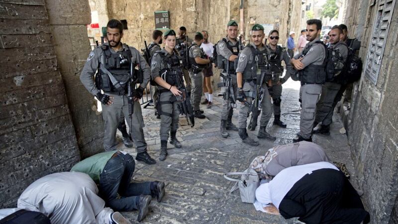 Israeli border police officers stand as Palestinians pray outside the Lion&#39;s Gate in Jerusalem&#39;s Old City. 