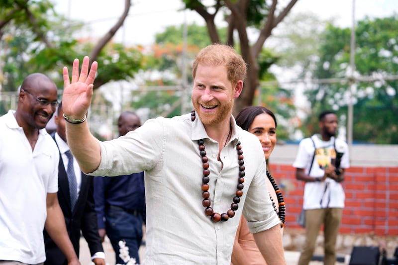 Harry gestures as he and Meghan visit children at the Lights Academy in Abuja (Sunday Alamba/AP)