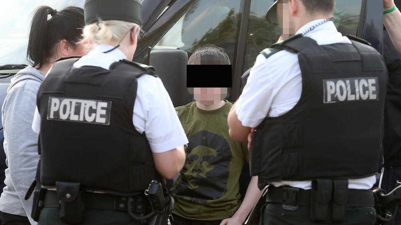 Police question a young boy after twelve men were arrested following an un-notified dissident republican parade in Lurgan, Co Armagh on Saturday. Picture by Mal McCann