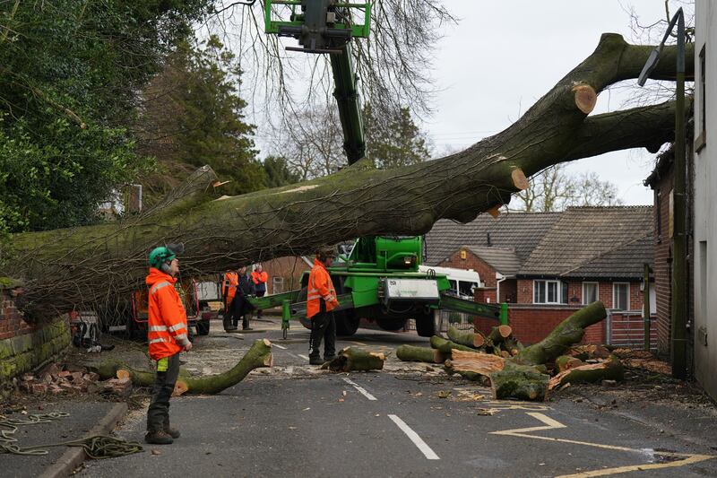 Workmen remove a fallen tree that has damaged the roof of a house in the village of Stanley in Derbyshire