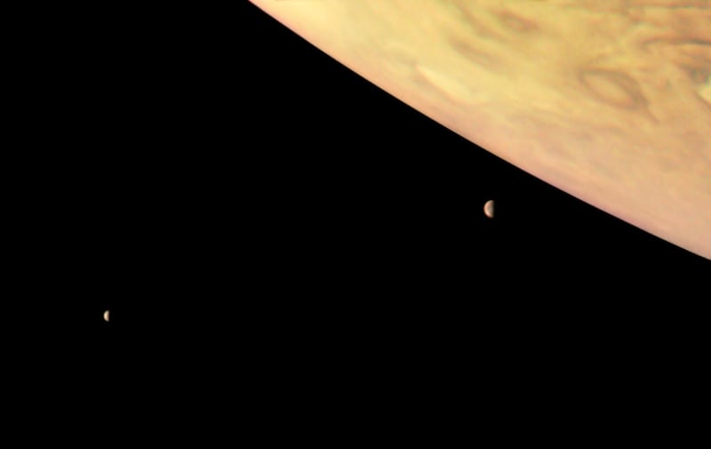 A portion of Jupiter and two of its moons