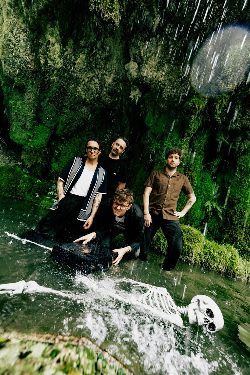 Leeds post-punks Yard Act posing in a pond with a skeleton