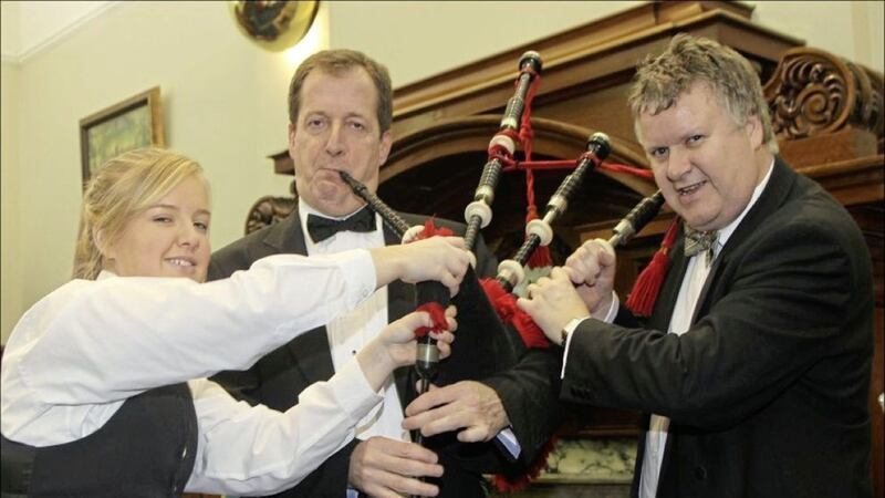 Gary McDonald and his daughter Cherry attempt to wrest their family bagpipes from Alastair Campbell at a NI Chamber of Commerce dinner in Belfast in December 2010 