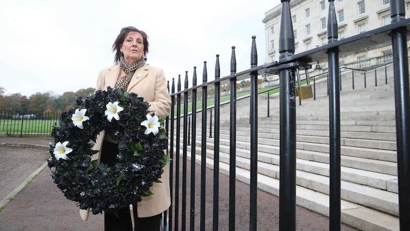 Anne Morgan, sister of Disappeared victim Seamus Ruddy, by locked gates to the steps of Stormont. Picture by Hugh Russell. 
