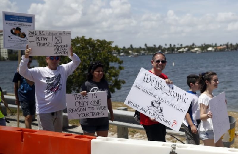 Protesters walk during a rally to encourage the release of President Donald Trump's tax returns, Saturday, April 15, 2017, in Palm Beach