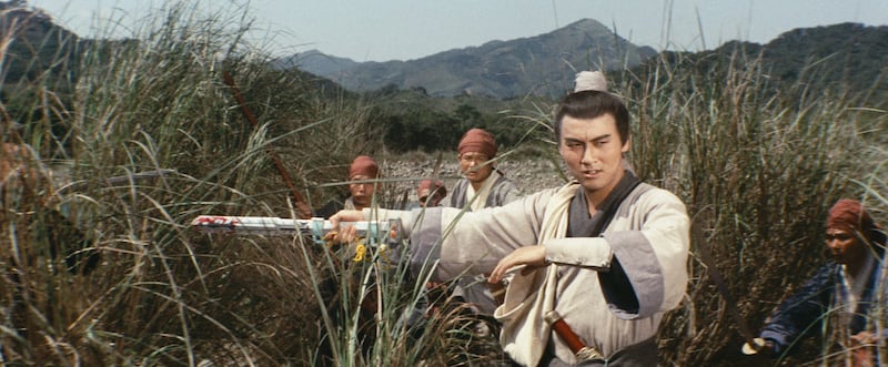 A scene from The Swordsman of All Swordsmen showing Tien Peng as Tsai Ying-jie moving through grassland with his sword drawn