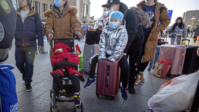 Travellers wear face masks as they walk outside of the Beijing Railway Station in Beijing Picture by Mark Schiefelbein/AP 
