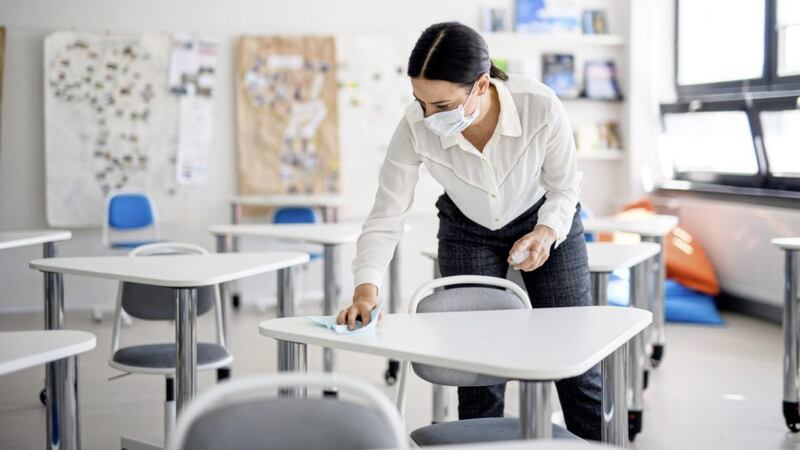 Teacher back at school after covid-19 quarantine and lockdown, disinfecting desks at break time.. 