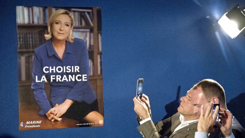 Members of National Front party take cellphone photos during a presentation of the new campaign poster and slogan of the far-right presidential candidate Marine Le Pen in Paris, France, Wednesday, April 26, 2017. Anti-European French presidential candidate Marine Le Pen upstaged her centrist opponent Emmanuel Macron by making a surprise campaign stop Wednesday to a home appliance factory that is the latest hot-button symbol of French job losses to plants overseas. (AP Photo/Michel Euler). 