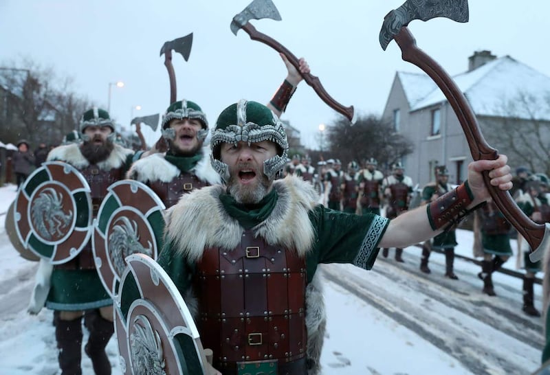 Members of the Jarl Squad cheers as they march through Lerwick as snow falls on the Shetland Isles during the Up Helly Aa Viking festival 