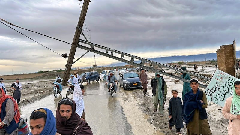 People pass by a damaged electric pole caused by flooding due to heavy rains in Pakistan (AP Photo/Habib Ullah)