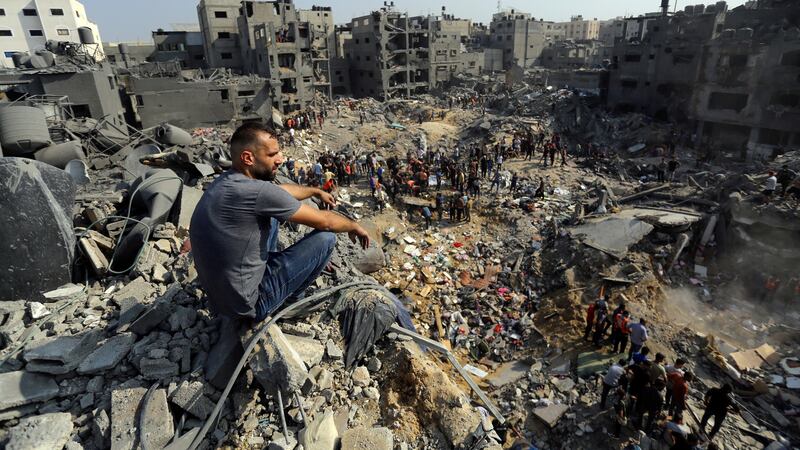 A man sits on the rubble as others wander among debris of buildings targeted by Israeli airstrikes in Jabaliya refugee camp, northern Gaza Strip, on Wednesday (Abed Khaled/AP)