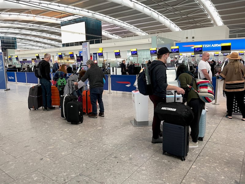 Passengers wait in line to check in at Terminal 5 of Heathrow Airport