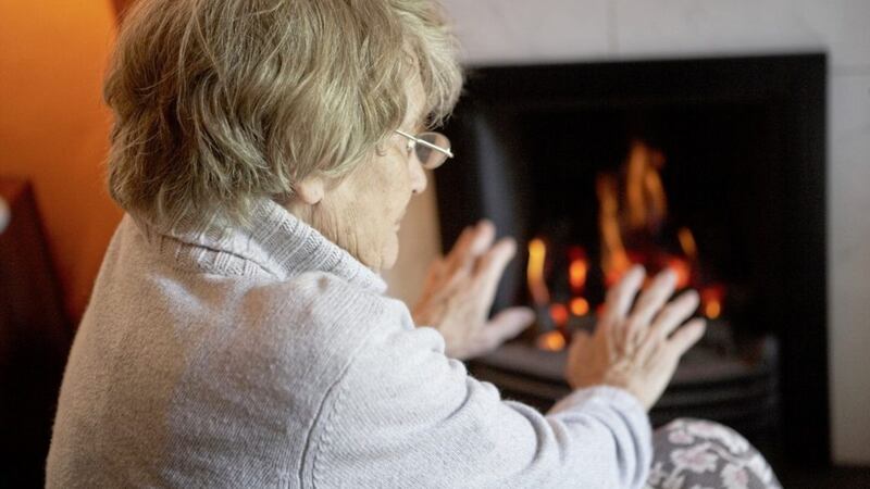 Senior Woman Warming Hands By Fire At Home 