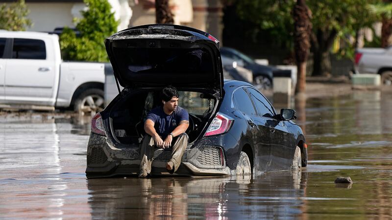 A man sits in his car as he waits for a tow after it got stuck in the mud (AP Photo/Mark J. Terrill)