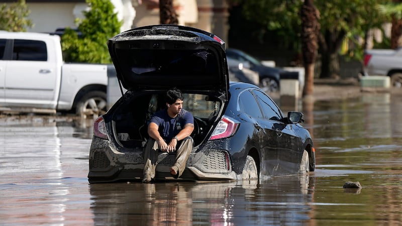 A man sits in his car as he waits for a tow after it got stuck in the mud (AP Photo/Mark J. Terrill)